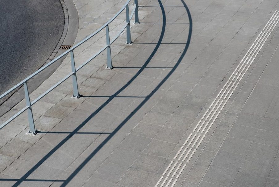 Concrete Walkway and Sidewalk Installation, aerial view of a modern sidewalk with metal railings and tactile paving for accessibility